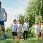Children in a park learning sports with a coach on a sunny day.