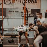 Group of athletes engaging in a competitive CrossFit workout at a gym with emphasis on strength and teamwork.